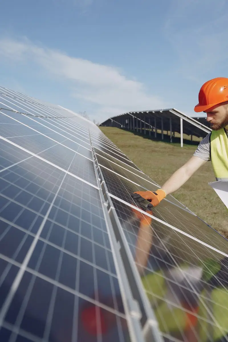 Technician in PPE inspects solar panels in a renewable energy field, promoting sustainability.